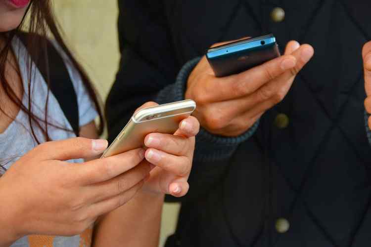 Two people using cellular devices trying to find a signal